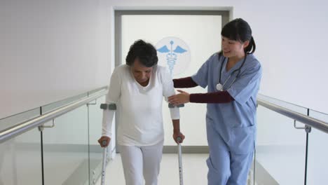 Young-doctor-helping-patient-use-crutches-in-hospital-4k