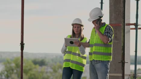 Der-Controller-ist-ein-Mann-eines-Gebäudes-im-Bau-sprechen-am-Telefon-mit-dem-Management-und-hat-mit-dem-Ingenieur-und-Architekt-Frau-Baufortschritt-diskutiert