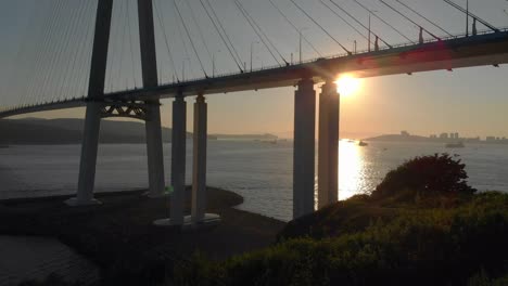 Toma-aérea-del-puente-de-cable-Russkiy-durante-la-puesta-del-sol-en-una-ciudad-de-Vladivostok,-Rusia