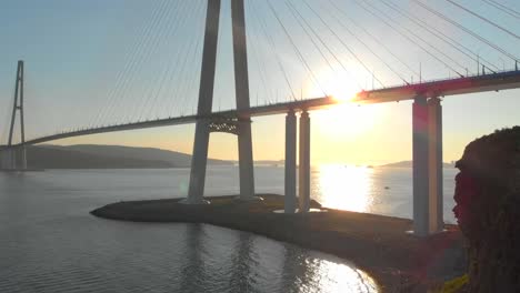 Toma-aérea-del-puente-de-cable-Russkiy-durante-la-puesta-del-sol-en-una-ciudad-de-Vladivostok,-Rusia