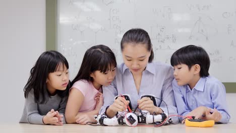 Gruppe-von-Schülern-und-Lehrern-in-der-Roboterklasse.-Berater-in-der-Studentin-über-ihr-Roboterprojekt-erklären.