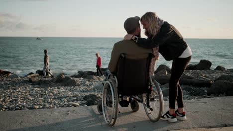 Frau-umarmt-ihren-geliebten-behinderten-Ehemann-am-Meer