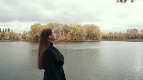 Girl-walks-along-the-waterfront-wake-with-yellow-maples-in-autumn.