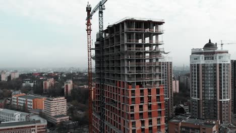 Grúa-de-construcción-en-obra.-Construcción-de-edificio-residencial-de-hormigón-ladrillo,-vista-de-dron-aéreo.-Casa-de-gran-altura-inacabada