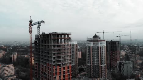 Luftaufnahme-des-Hochhausbaus-aus-Beton.-Wohnkomplexbau-in-der-Großstadt.-Drohne-fliegt-in-der-Nähe-von-unvollendetem-Backsteingebäude