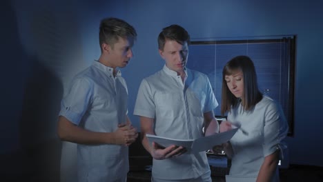 Three-doctors-look-at-an-x-ray-photo-of-a-patient-together.-Joint-work-of-the-team-of-doctors-of-the-clinic.-Doctor's-work-with-interns.