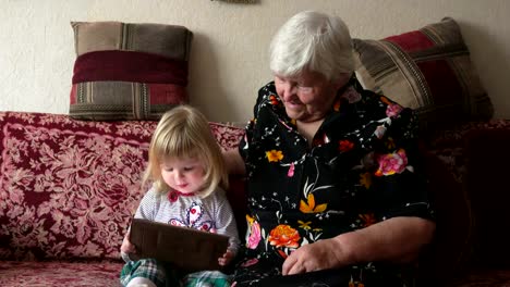 Girl-sit-with-her-grandmother-and-watch-tablet