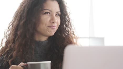 Mujer-de-negocios-bebiendo-café-y-video-chat-usando-computadora-portátil-de-oficina