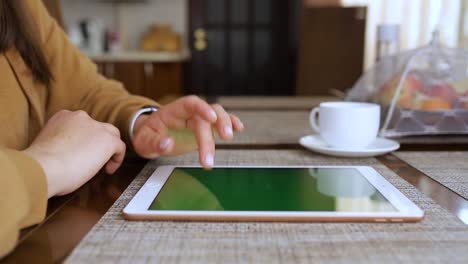 Girl-checks-e-mails-on-a-tablet-while-drinking-tea-in-her-kitchen