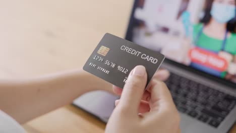 Close-up-consumer-woman's-hand-holding-credit-card-making-e-bank-online-payment-for-purchase-in-online-website-store-with-laptop-computer.-Ecommerce-website-payments.-new-normal-digital-lifestyle