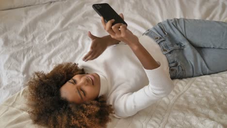 Lady-lies-on-bed-holding-smartphone-and-shooting-video-blog