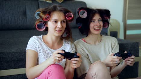 Zwei-lustige-Frauen-spielen-Konsolenspiele-mit-Gamepad-und-haben-Spaß-zu-Hause