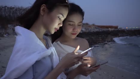 Two-women-stand-play-the-phone-at-night.-Technology-concepts-can-communicate-anywhere.