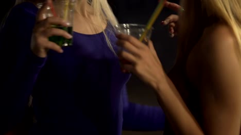 Flirty-seductive-women-drinking-cocktails,-dancing-and-hugging-in-night-club