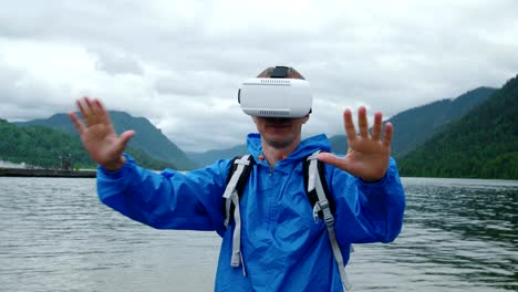 Ein-Mann-nutzt-virtual-Reality-Brille-auf-dem-Hintergrund-eines-Bergsees