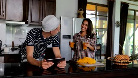 Couple-Use-Tablet-Computer,-Young-Woman-And-Man-In-Kitchen-Studio-Chatting-Online-Drink-Juice-Modern-House-Interior