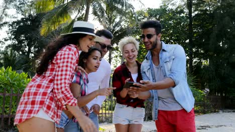 Grupo-de-personas-uso-celular-teléfonos-hablando-a-los-hombres-inteligentes-y-mujeres-palmeras-tropicales-ver-fotos