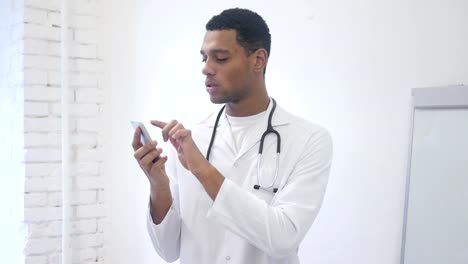 Africano-americano-Doctor-navegación-Smartphone-en-Hospital