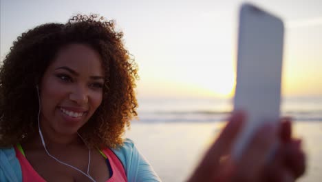 Ethnic-female-taking-photo-on-beach-at-sunrise