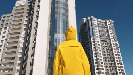 Alguien-en-impermeable-amarillo-permanecer-frente-a-edificio-de-la-moderna-zona-residencial