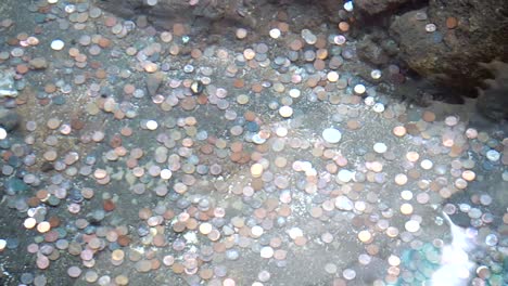 Coins-on-the-bottom-of-a-wishing-well-fountain-in-slow-motion