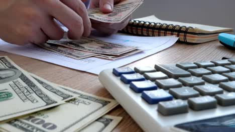 Man-in-the-office-counting-money.-Dollar-bills-on-a-table.