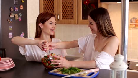 Dos-hermanas-preparan-una-ensalada-en-la-cocina-en-la-mañana.