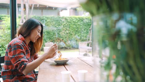 Beautiful-happy-Asian-women-lesbian-lgbt-couple-sitting-each-side-eating-a-plate-of-Italian-seafood-spaghetti-and-french-fries-at-restaurant-or-cafe-while-smiling-and-looking-at-food.