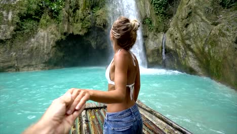 Follow-me-to-concept-young-woman-leading-boyfriend-to-amazing-waterfall,-shot-in-Cebu-Island,-Visayas-Islands,-Philippines.-Idyllic-tropical-travel-journey-vacations-concept.-Slow-motion-video