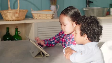 Niña-asiática-y-africano-niño-usando-la-tableta-juntos