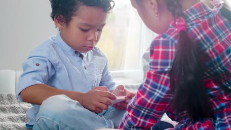 Multiethnische-Kinder-spielen-auf-Smartphone-auf-Bett