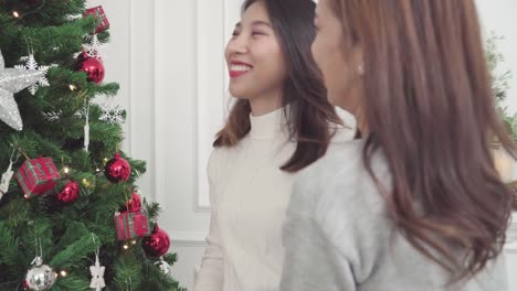 Sentimiento-de-pareja-asiática-lesbiana-feliz-decoración-árbol-de-Navidad-en-su-sala-de-estar-en-el-país-en-el-Festival-de-Navidad.-Las-mujeres-del-estilo-de-vida-lgbt-felizes-celebran-Navidad-y-año-nuevo-concepto.