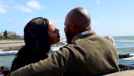 Couple-kissing-on-bench-near-railing-on-a-sunny-day-4k