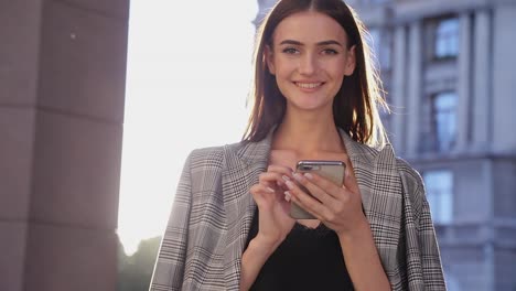 Mujer-de-negocios-hermosa-usando-teléfono-móvil-al-aire-libre-en-día-soleado