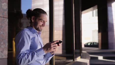 Business-Man-Using-Mobile-Phone-Near-Office-Building