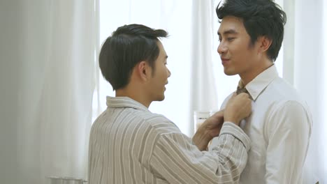 Lovely-gay-couple,-man-helps-to-put-on-a-tie-for-his-boyfriend.-In-slow-motion.-People-with-gay,-homosexual,-lifestyle-and-relationship-concept.