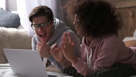 Couple-dancing-while-watching-media-content-on-laptop-in-bed