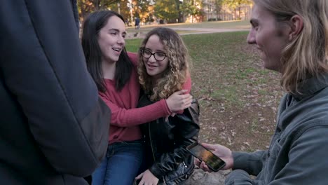 Two-young-women-with-their-arms-around-each-other-sitting-outside-college-campus