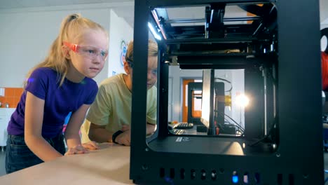 Excited-school-kids-using-three-dimensional-printer-for-creating-3D-printed-robot.