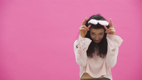 Festive-Easter-holiday-season.-Smiling-young-woman-in-Easter-bunny-ears-on-pink-background-jumping-and-looking-at-copy-space.