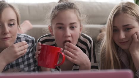 Mädchen-beobachten-Medieninhalte-auf-dem-Laptop,-während-sie-Essen-und-Trinken-haben