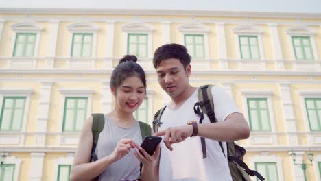 Traveler-Asian-couple-direction-on-location-map-in-Bangkok,-Thailand,-couple-using-mobile-phone-looking-on-map-find-landmark-while-spending-holiday-trip.-Lifestyle-couple-travel-in-city-concept.