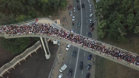 Eine-Menschenmenge-auf-einer-Fußgängerbrücke-ist-am-Frühlingsabend-zu-sehen.-Luftaufnahme.-Eine-neue-Fahrrad-Fußgängerbrücke-im-Zentrum-der-Hauptstadt-der-Ukraine,-der-Stadt-Kiew.-Ausflüge-und-Spaziergänge-für-Touristen