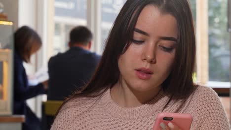 Attractive-woman-drinking-coffee,-using-her-smart-phone-at-the-cafe