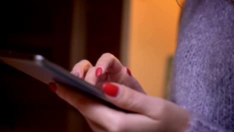 Closeup-shoot-of-female-hands-typing-on-the-tablet-in-a-cozy-apartment-indoors