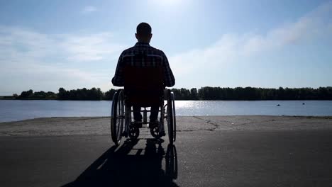 Un-hombre-en-silla-de-ruedas-camina-en-el-paseo-marítimo