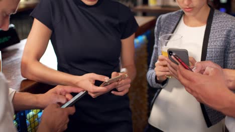 Gruppe-von-Geschäftskollegen-alle-überprüfen-Handys-während-Treffen-zum-Trinken-in-Bar