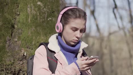 Caucasian-girl-in-the-forest-with-a-mobile-phone.-Young-tourist-on-vacation-in-the-forest