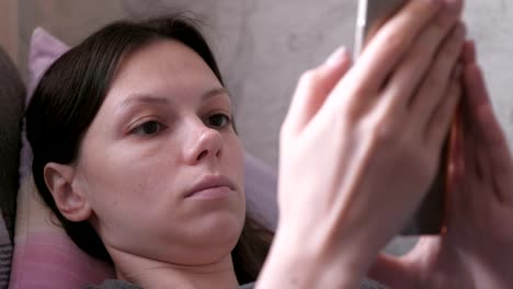 Tense-woman-lying-on-the-couch-and-reading-something-at-the-mobile-phone.