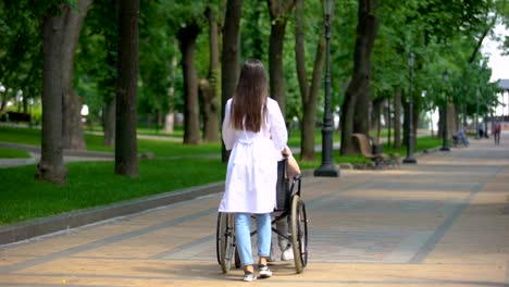 Enfermera-que-camina-en-el-parque-con-paciente-discapacitado,-centro-de-rehabilitación